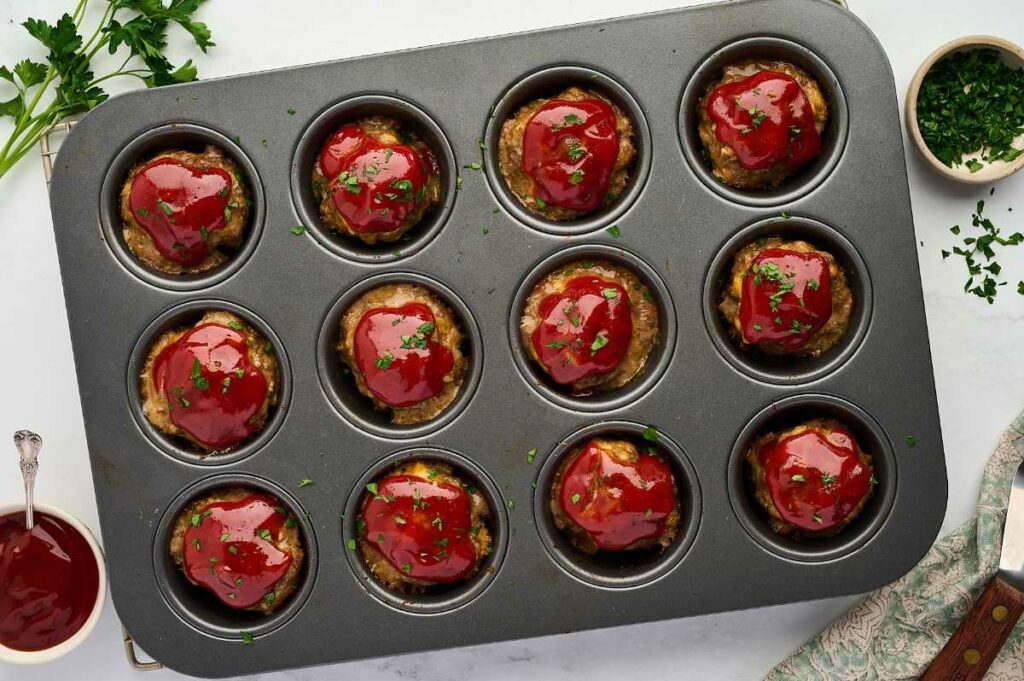 Twelve mini meatloaf muffins in a muffin pan topped with sweet glaze.