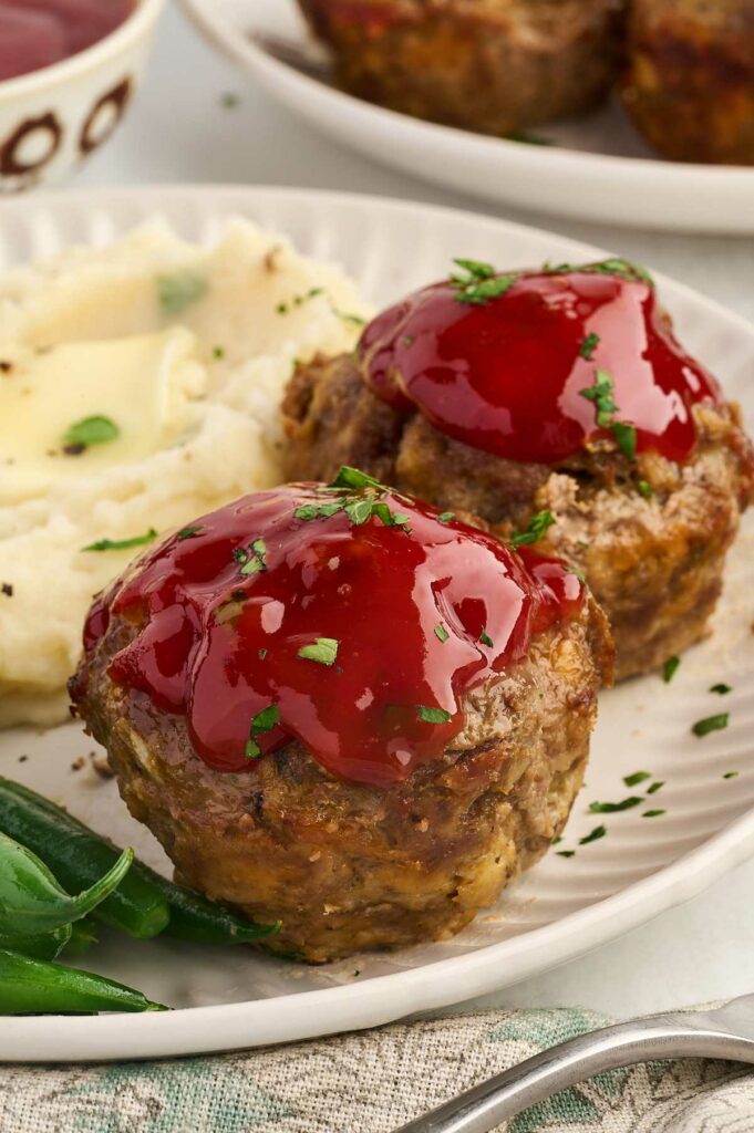 Two muffin pan meatloaf servings on a dinner plate.