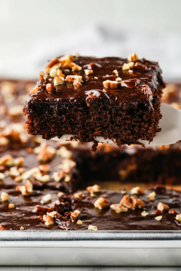 A spatula lifting a slice of texas sheet cake recipe from a pan.