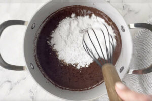 Adding powdered sugar to the chocolate icing.