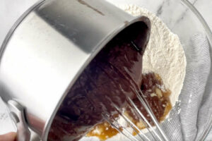 Pouring warm cocoa mixture into the flour mixture.