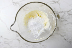 Adding powdered sugar to buttercream.