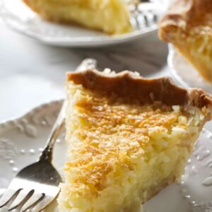 Custard pie slice with golden crust on a plate, fork beside it.