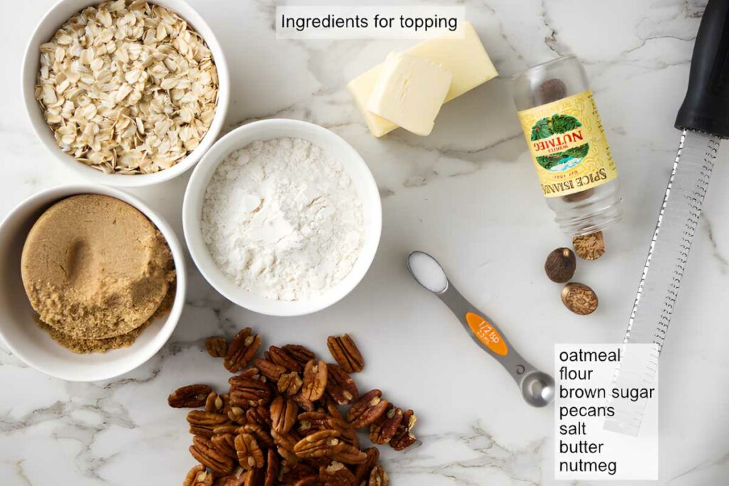 Oatmeal topping ingredients: oats, flour, brown sugar, pecans, butter on marble.