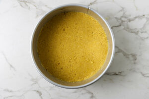 Pressing cookie crumbs into the bottom of a spring form pan.