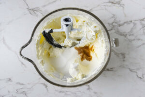 Adding sugar and vanilla to the cream cheese mixture.