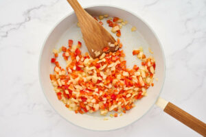Cooking onions and bell peppers in a skillet.