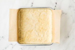Pressing the shortbread crust into a baking pan.
