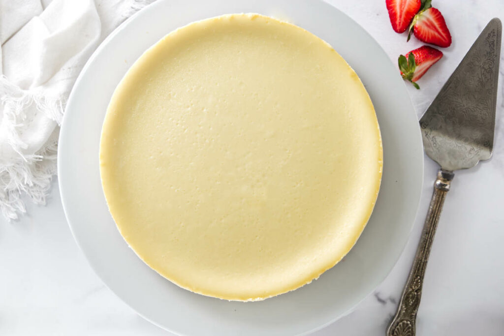 A perfectly smooth cheesecake on a plate showing no cracks.