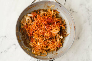 Sautéing onion and bacon in a skillet.