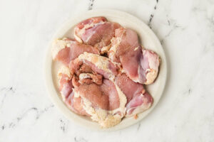 seasoning the chicken on a plate.