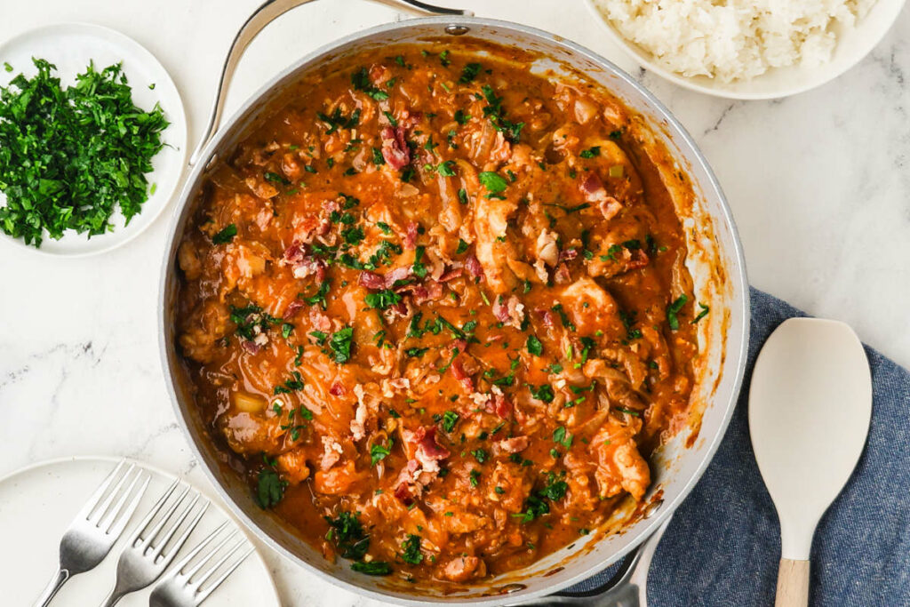 Smothered chicken in a onion gravy next to a bowl of rice.
