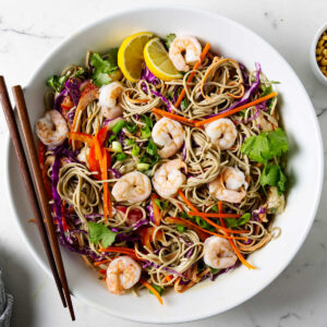 A serving bowl filled with a shrimp and soba noodle salad.
