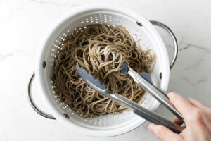 Cooked soba noodles in a colander.