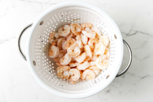 Cooked shrimp in a colander.