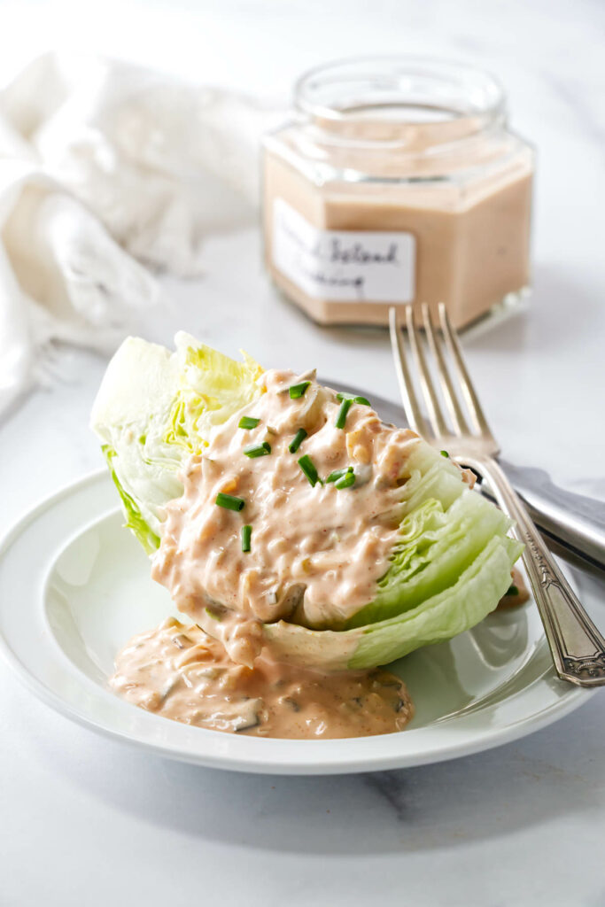 Thousand Island salad dressing on a wedge of lettuce next to a fork.