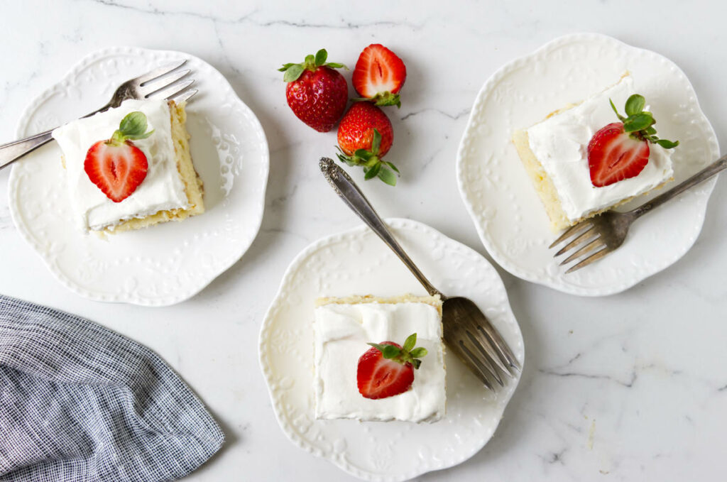 An overhead view of three slices of Mexican leche cake on a marble counter.