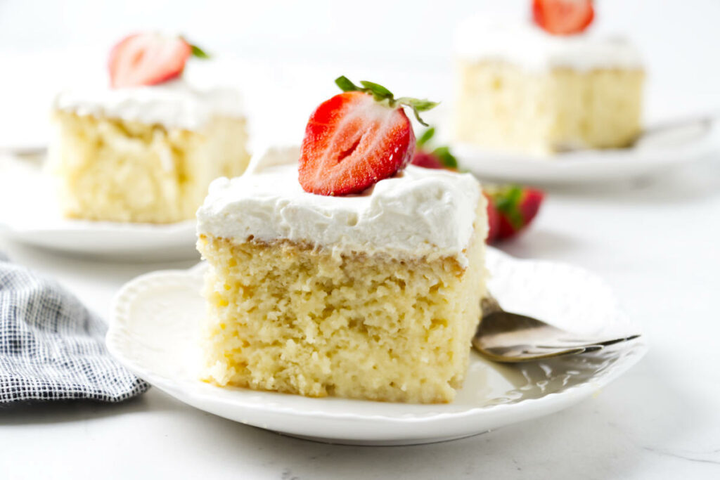 A slice of Mexican leche cake on a white plate.