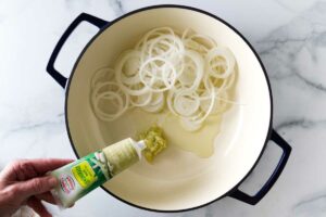 Adding lemongrass past to a skillet with onions.