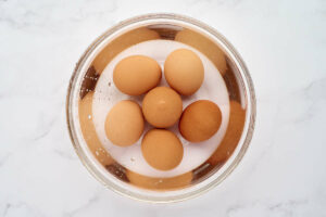Brown eggs in a bowl of warm water.