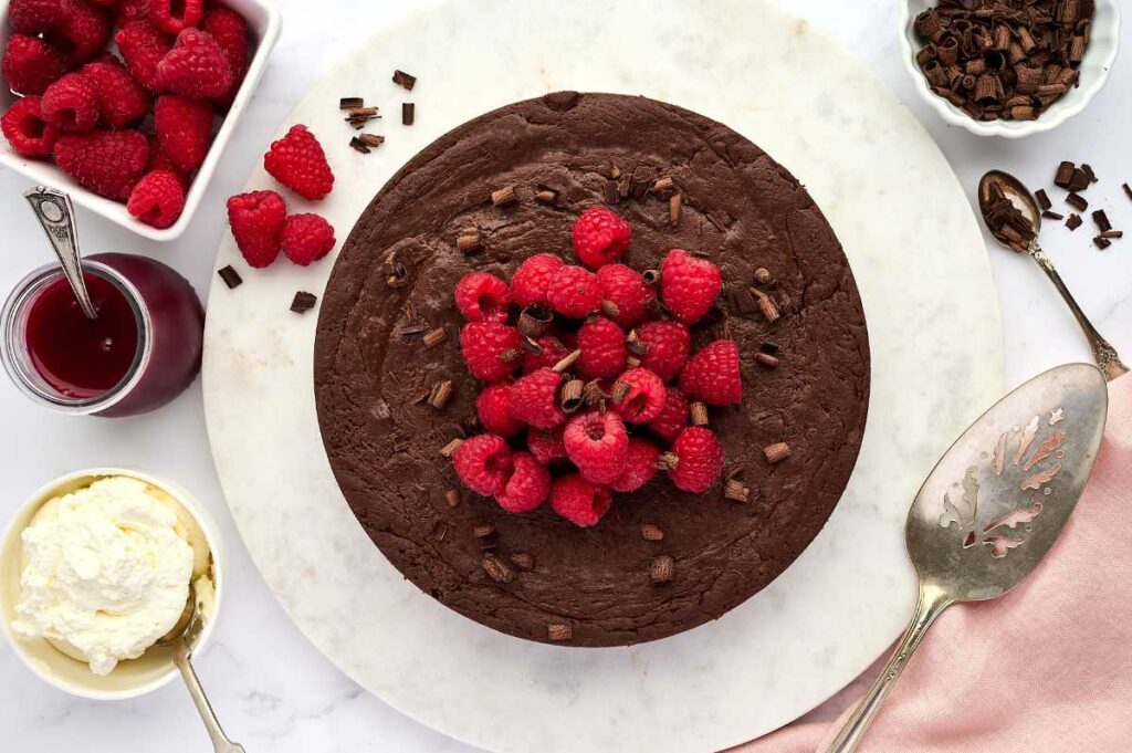 Overhead view of a chocolate torte topped with fresh raspberries.