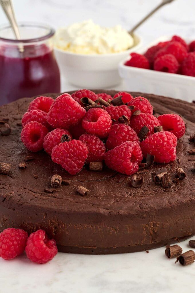 A chocolate torte cake topped with raspberries.