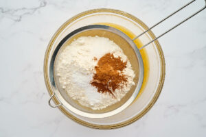 Sifting the dry ingredients over the bowl of wet ingredients.