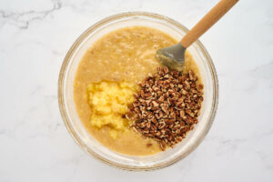 Adding crushed pineapple and toasted pecans to the cake batter.