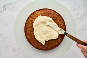 Spreading the frosting on the layer cake.