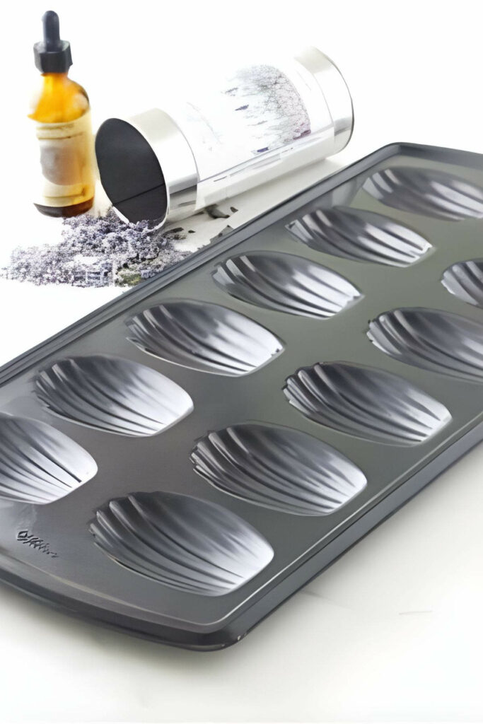 A metal madeleine pan next to a jar of dried lavender buds.