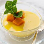 A mango posset dessert in a dish topped with sliced mango.