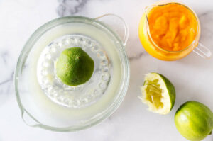 Juicing limes in a clear glass dish.