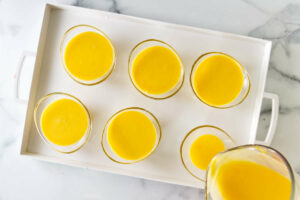 Pouring the posset dessert into small dishes.