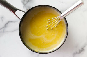 Whisking the posset cream in a pot.