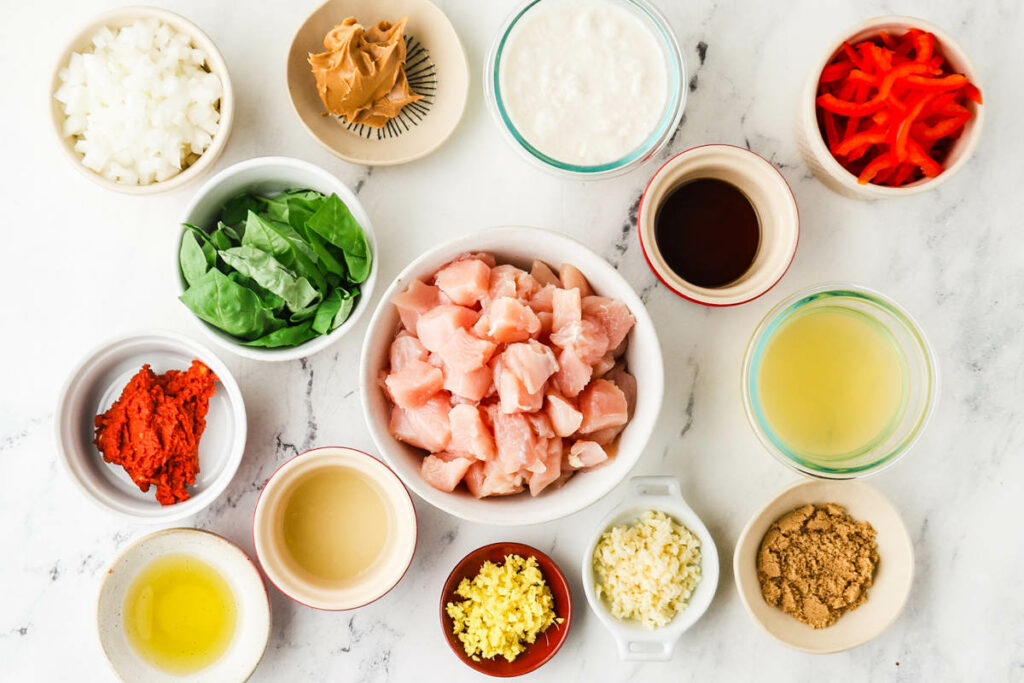 Overhead view of assorted cooking ingredients in bowls, including chicken and vegetables.