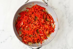 Cooking bell pepper and curry paste in a skillet.