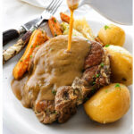 Pork chops with gravy, potatoes, carrots, and cabbage on a plate.