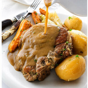 Pork chops with gravy, potatoes, carrots, and cabbage on a plate.