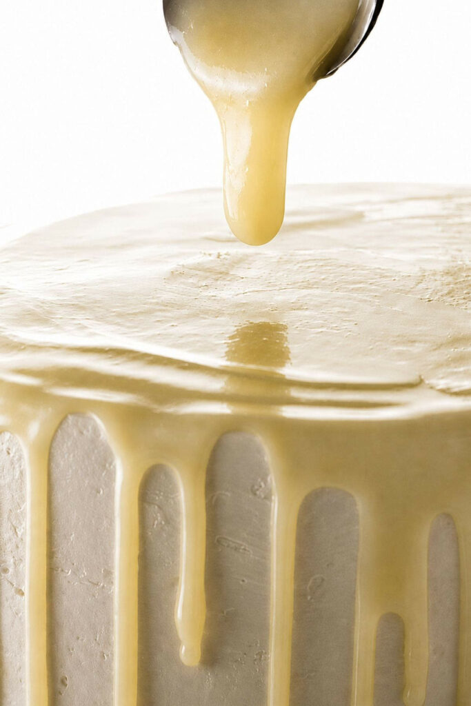 Drizzling a white ganache recipe over a layer cake.