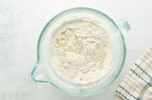 Adding the liquid to the mixing bowl with flour.