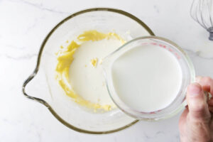 Pouring warm milk into the custard cake batter.