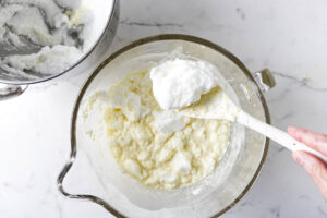 Folding whipped egg whites into vanilla custard batter.
