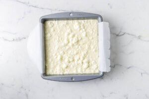 Custard cake batter in a square cake pan prior to baking.