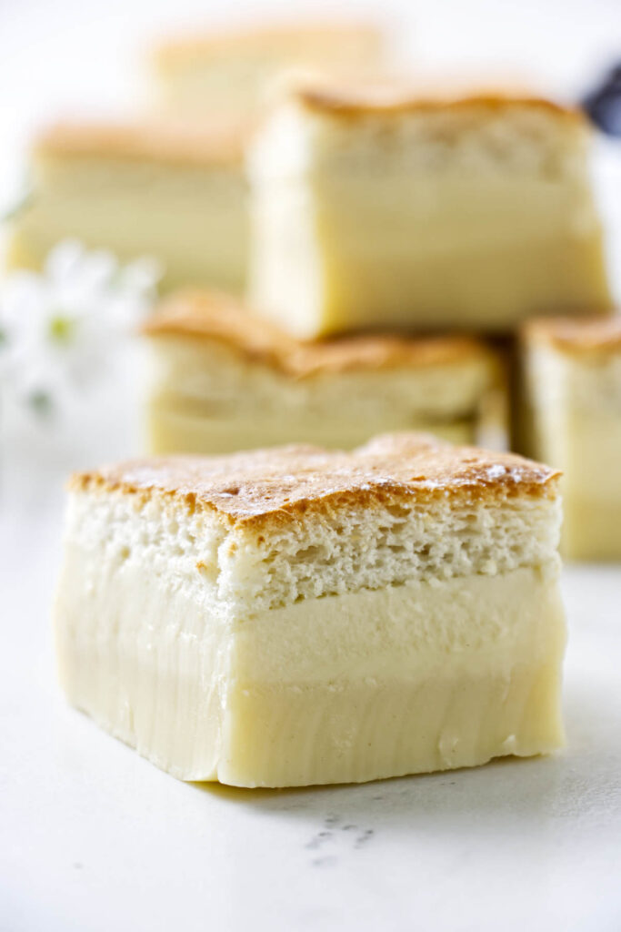 A slice of custard cake on a counter in front of several more slices.