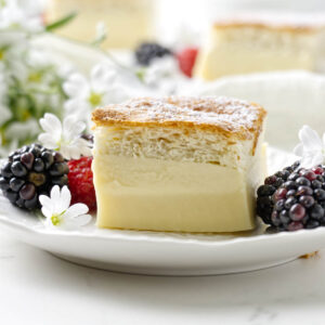 Close-up of a three-layer magic custard cake slice served with berries.