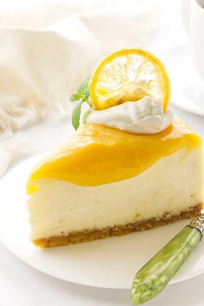 Slice of lemon cheesecake with lemon curd topping on a plate.