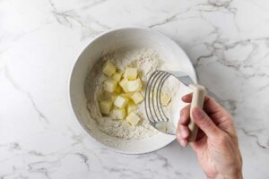 Cold butter being cut into flour for blueberry cobbler biscuit topping.
