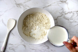 Heavy cream being added to biscuit topping mixture for blueberry cobbler.