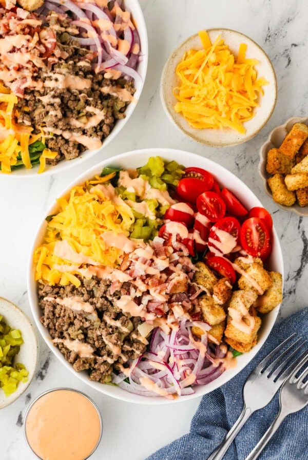 Deconstructed cheeseburger salad topped with diced tomatoes, pickles, and Thousand Island dressing.