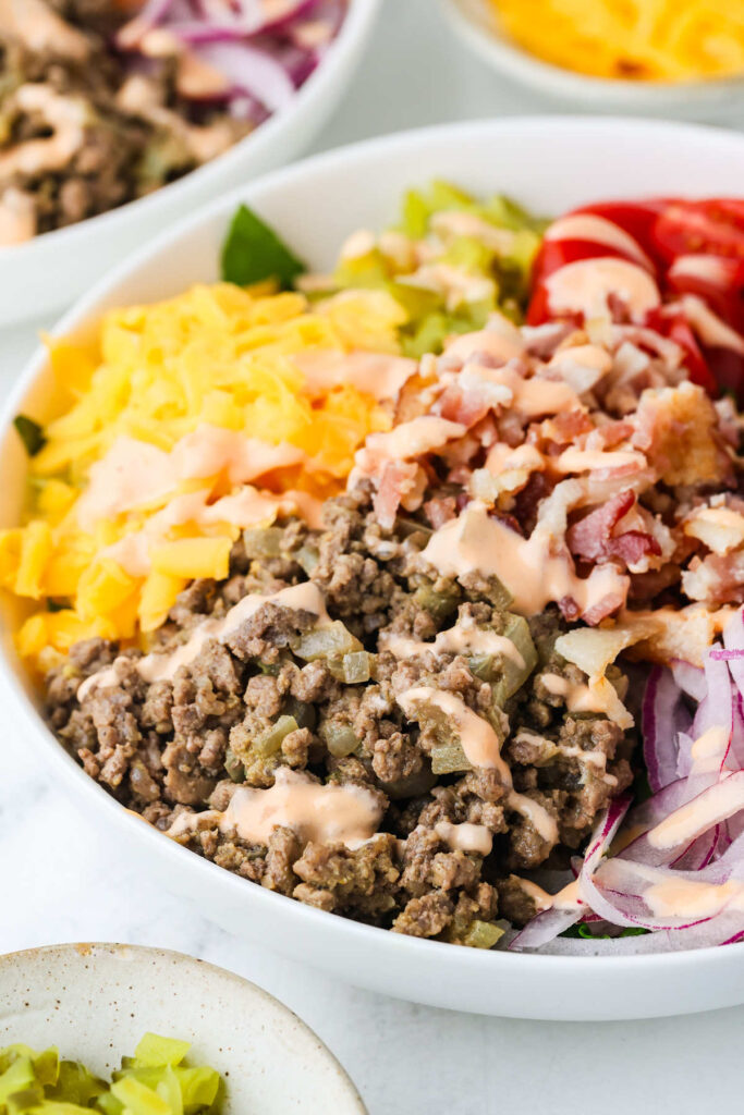 Low-carb cheeseburger salad with burger toppings on a bed of shredded lettuce.